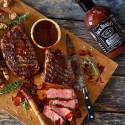 Viande sur une plancha à découper avec de une bouteille de sauce barbecue Original Jack Daniel's