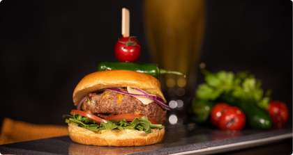 Burger avec un steak, de la salade, des oignons et des tomates, préparé au barbecue