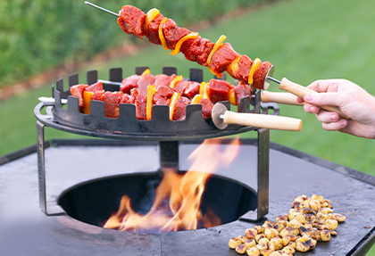 Cuisson de brochettes au dessus des flammes sur le brasero plancha Nestor noir Barbecook