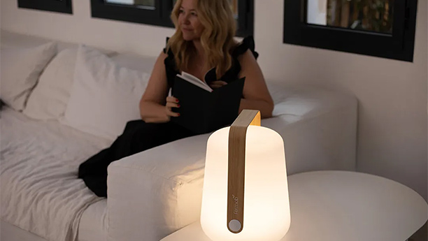 Lampe Balad Bamboo h38 Fermob qui éclaire une dame lisant dans un salon