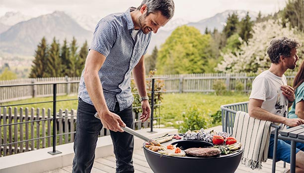 Préparation d'aliments sur le brasero Bowl 57 Höfats avec la demi-plaque de cuisson en fonte émaillée