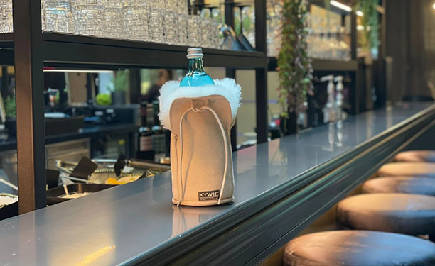 Refroidisseur pour bouteille de champagne en suède beige Kywie posé sur un bar