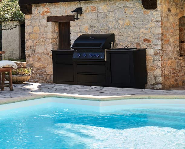 Cuisine extérieure Napoléon Oasis Compact noire BIG 32 au bord d'une piscine