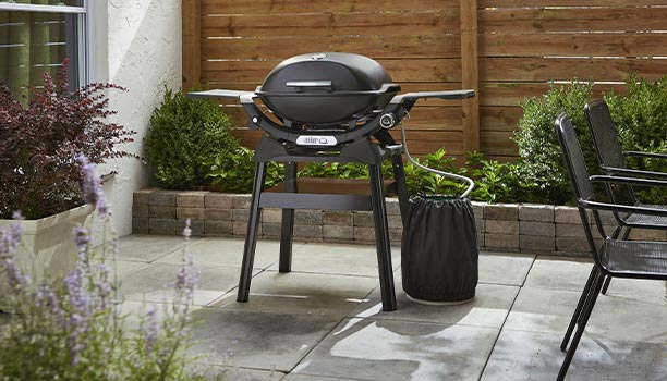 Barbecue gaz Q 2200 N noir sur stand Weber sur une terrasse extérieure