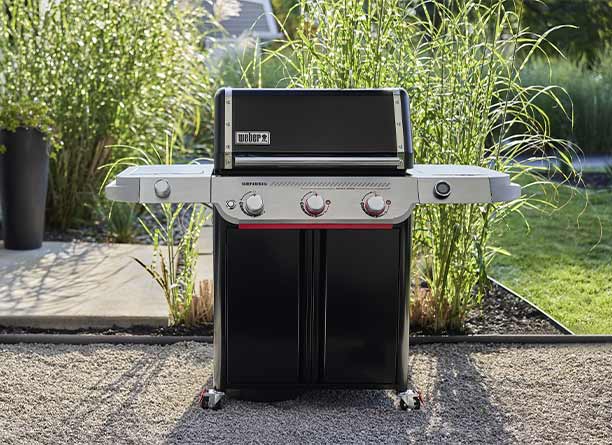 Barbecue gaz Genesis E-335 Weber exposé sur une allée avec des cailloux